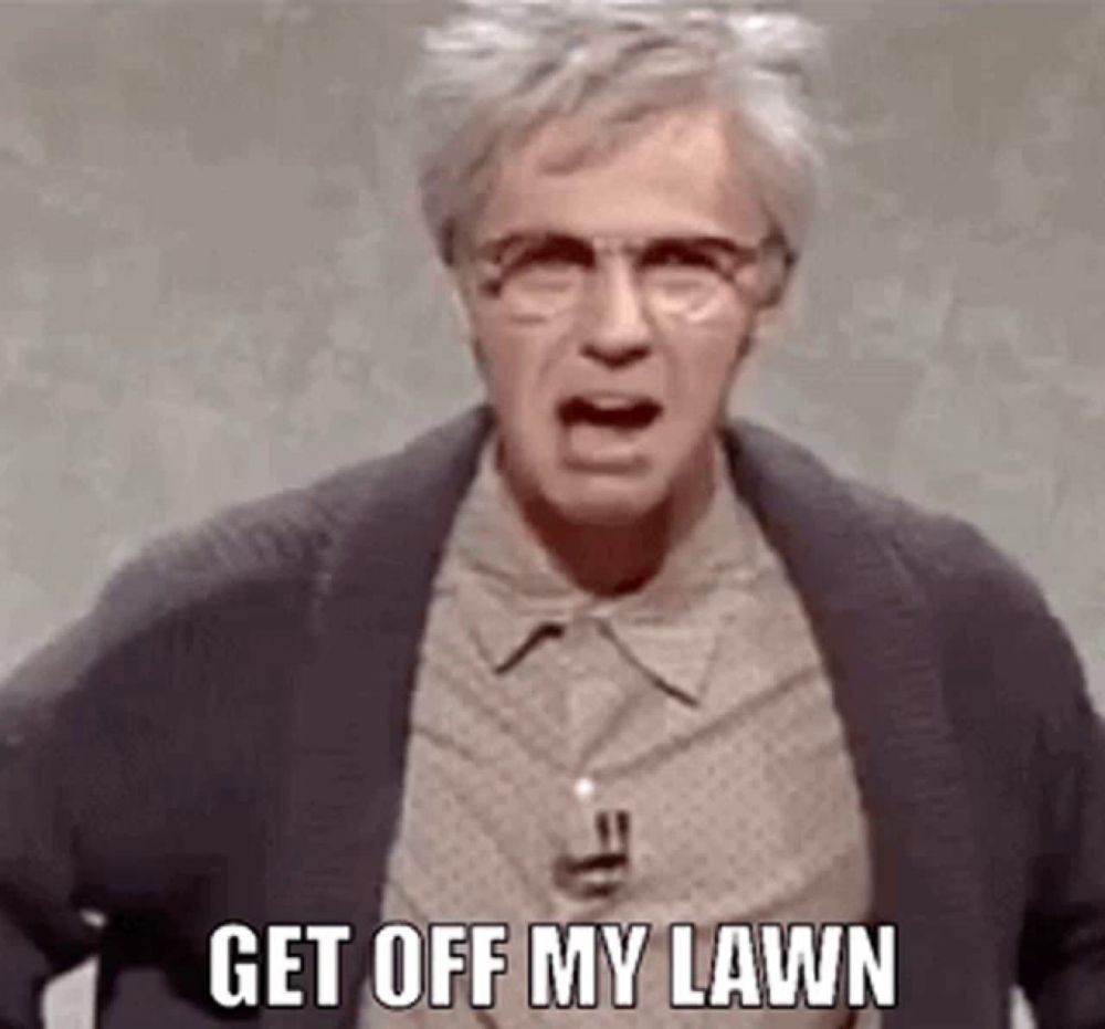 a man wearing glasses and a suit is yelling at someone and says `` get off my lawn '' .