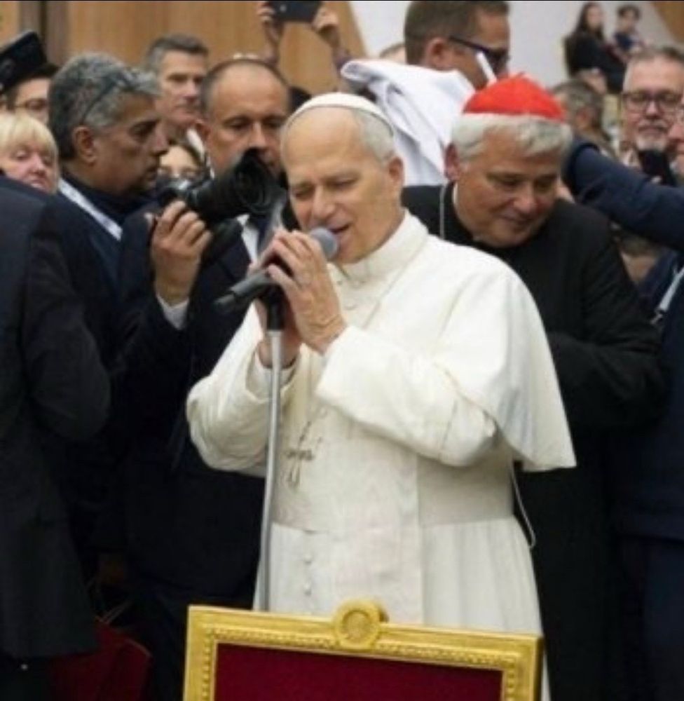 The Pope appears to be soulfully singing into a mic