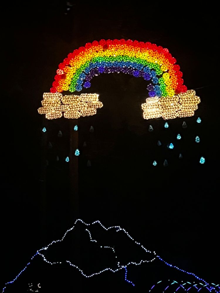 Light display of rainbow with clouds on either end, raining on a mountain. It's all lights! It was so high up in the air! 