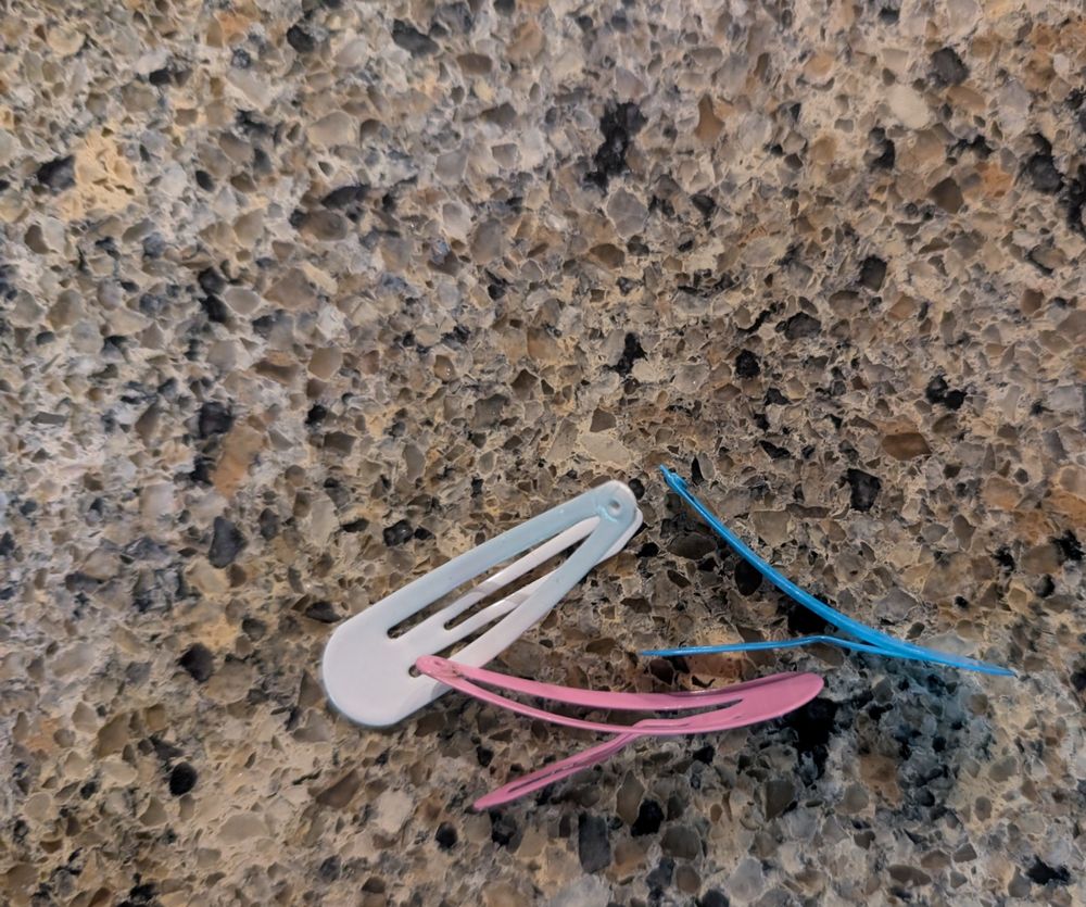 A pink, light blue and white barrette on a mottled granite counter.