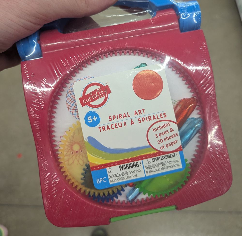 Hand holding a small spirograph in a store.