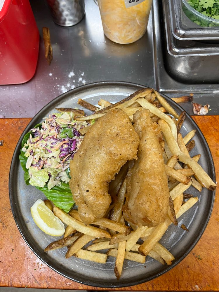 Fish and chips on a bed of fries with slaw