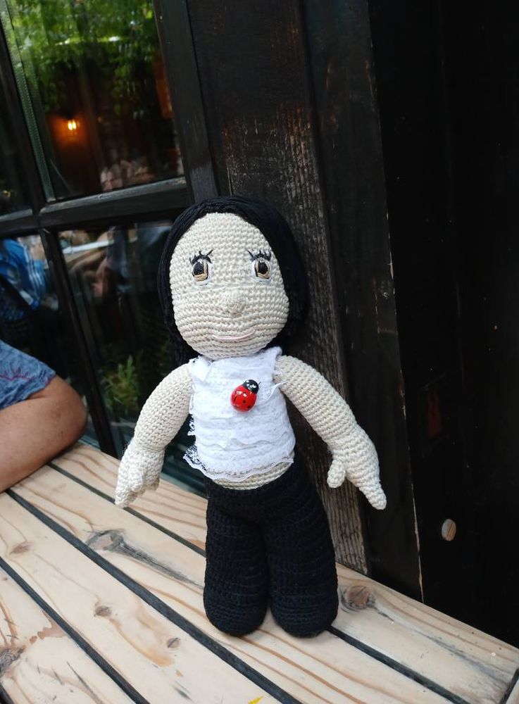 Amigurumi crocheted stuffed boy on a table outside the restaurant.