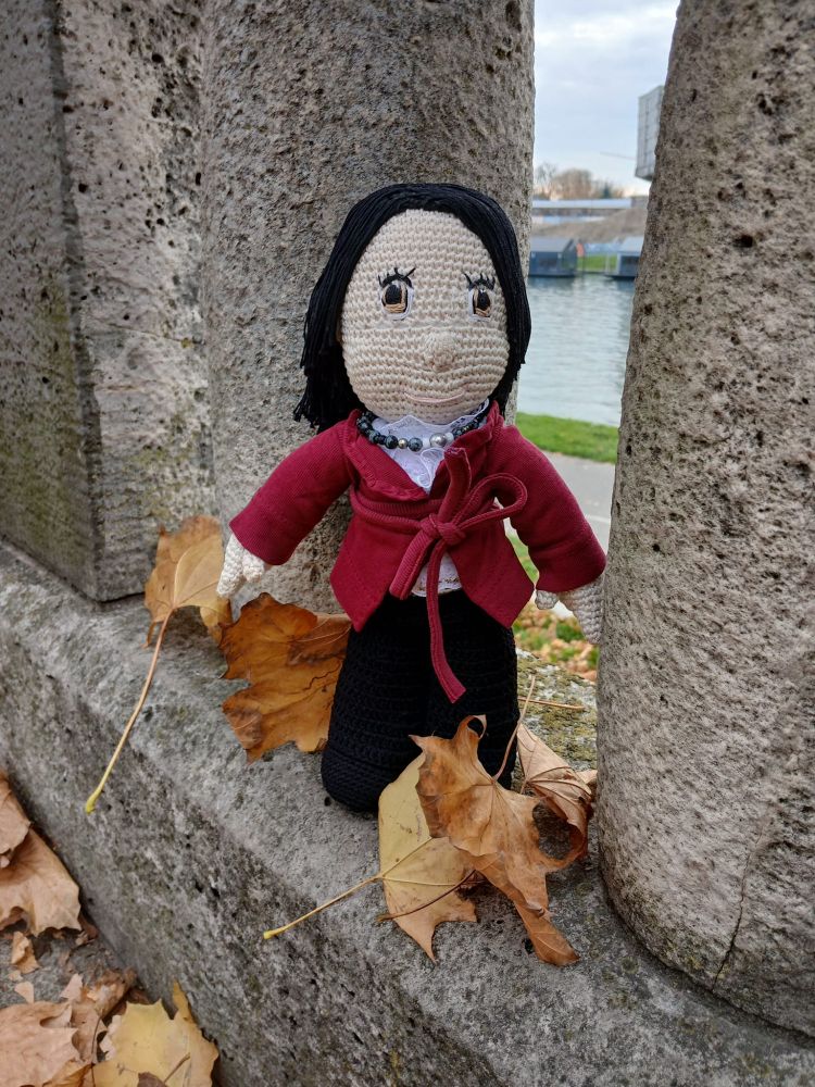 Amigurumi crocheted stuffed boy outside among the autumn leaves.