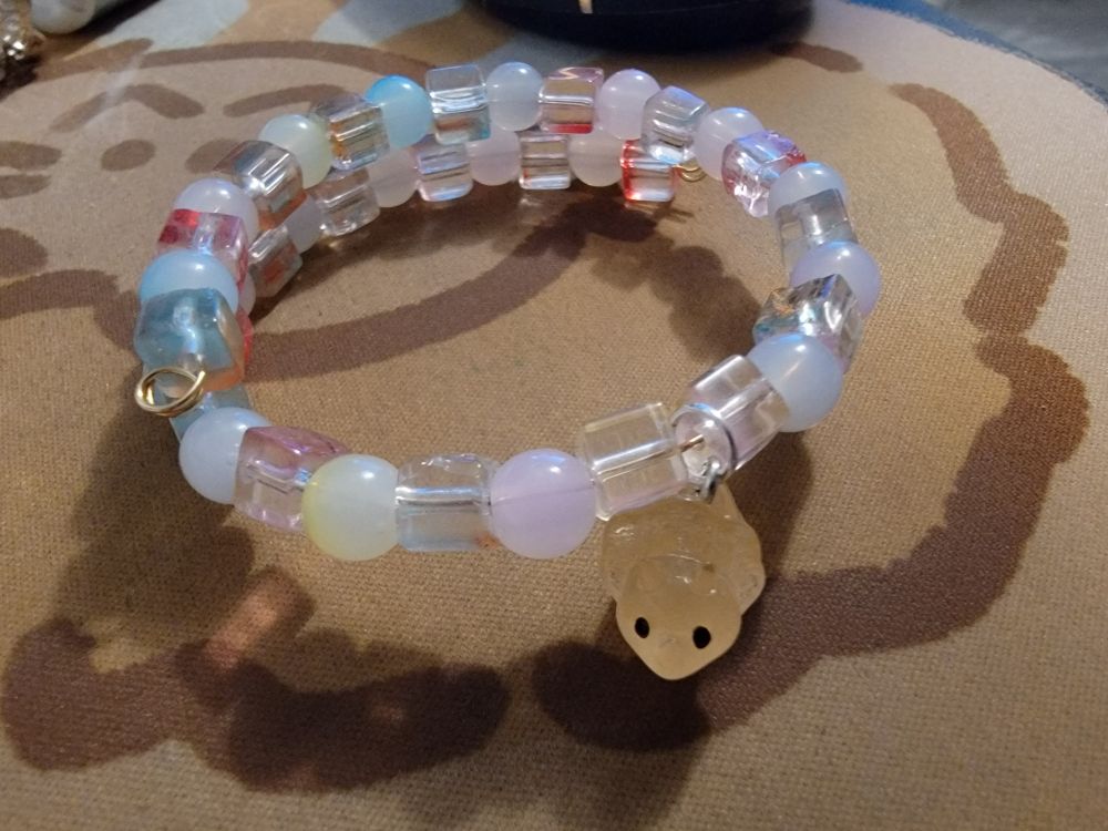 Rainbow bracelet with pastel round beads and clear cube beads with an orange triceratops charm