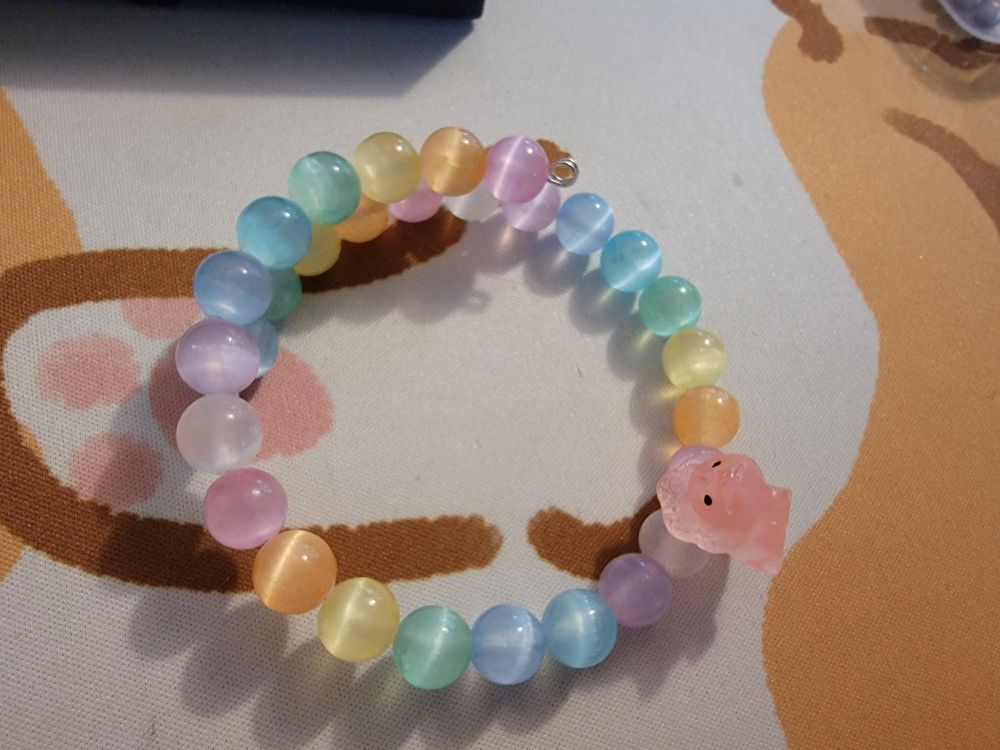 Rainbow bracelet with tiger eye pattern beads, and a pink triceratops charm