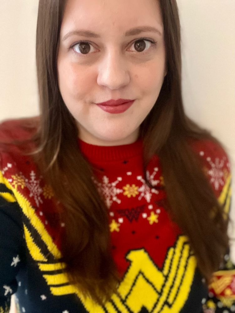 Picture is of me, a white woman in her 30’s with long brown hair and brown eyes. Wearing a festive print Wonder Woman Christmas jumper. 