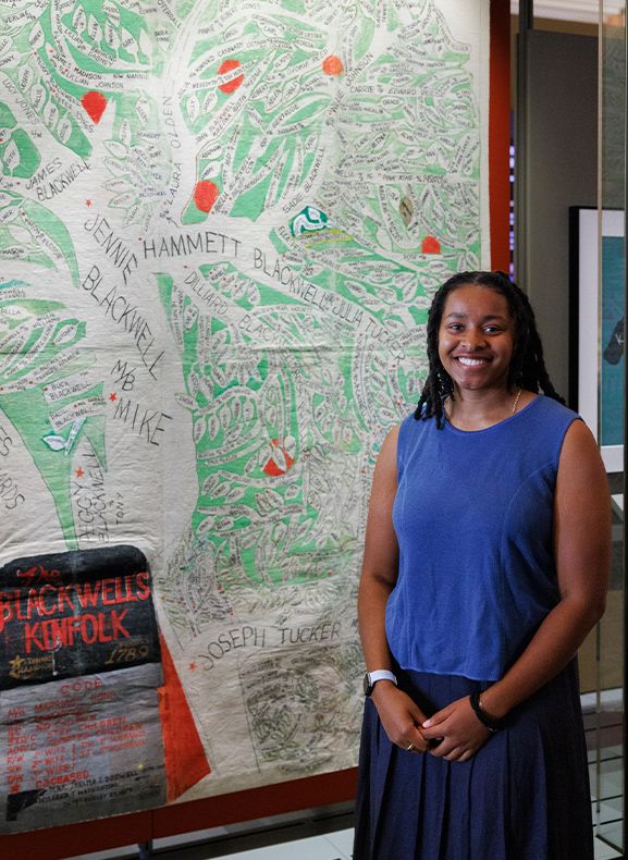Mila Hill, a 2024 junior fellow in the Library of Congress Office of Communications, poses with the Blackwell's Kinfolk Family Tree. Blackwell is a family name on her mother's side of the family, and she learned during her fellowship that this Library treasure represents part of her own family.
