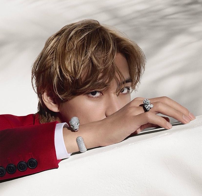 A photo of blonde Kim Taehyung wearing a red suit and silver jewelry - from his Cartier shoot.  
