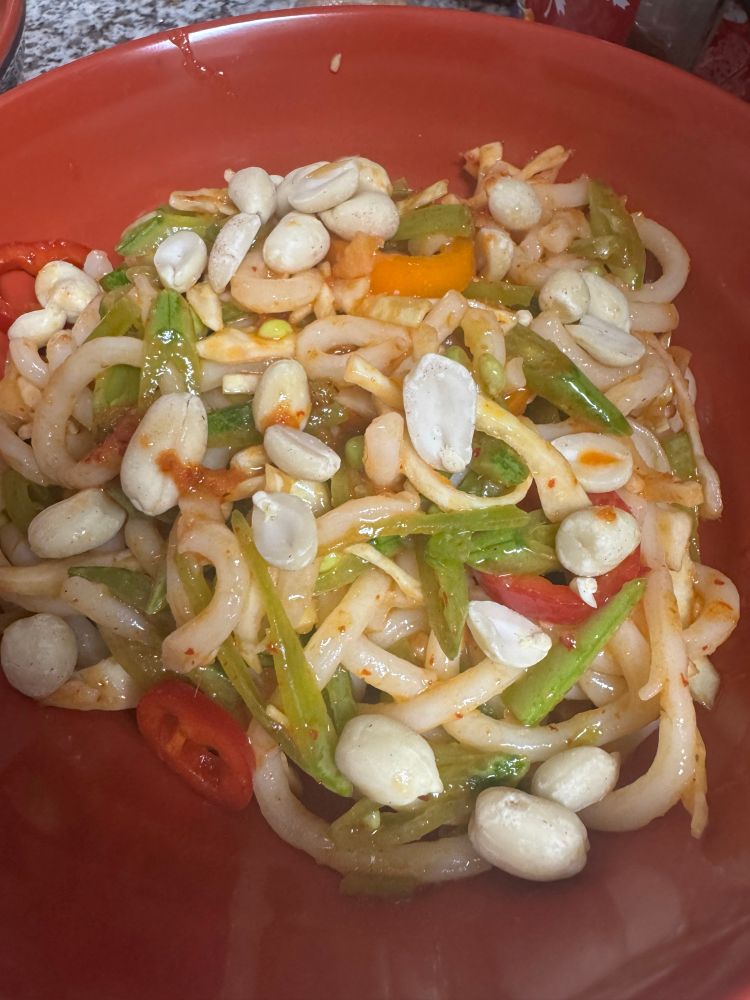 A bowl of udon noodles with sweet peppers, sugar snap peas, cabbage, and peanuts in a curry vinaigrette 