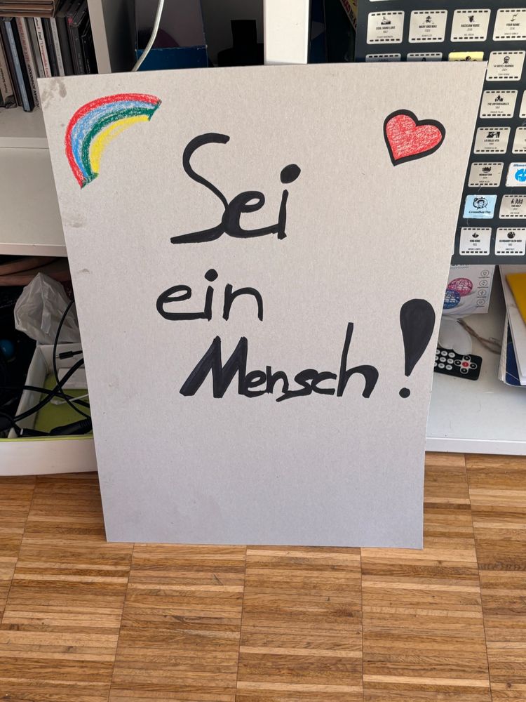 Man sie ein Plakat mit der Aufschrift: „Sei ein Mensch“