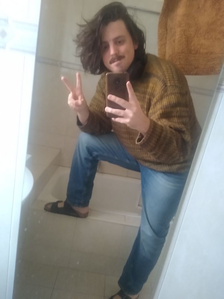 It's me in a bathroom mirror selfie wearing a big yellow jumper and blue jeans