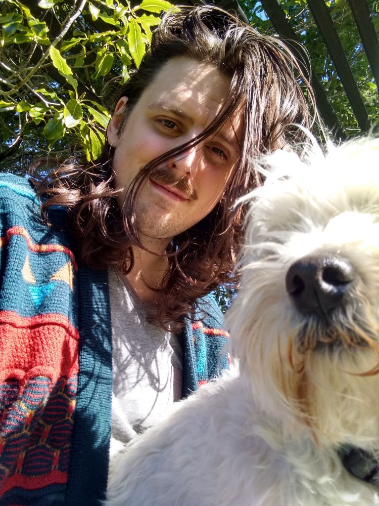 It's me on a sunny garden bench with a tree in the background and a little dog in my lap