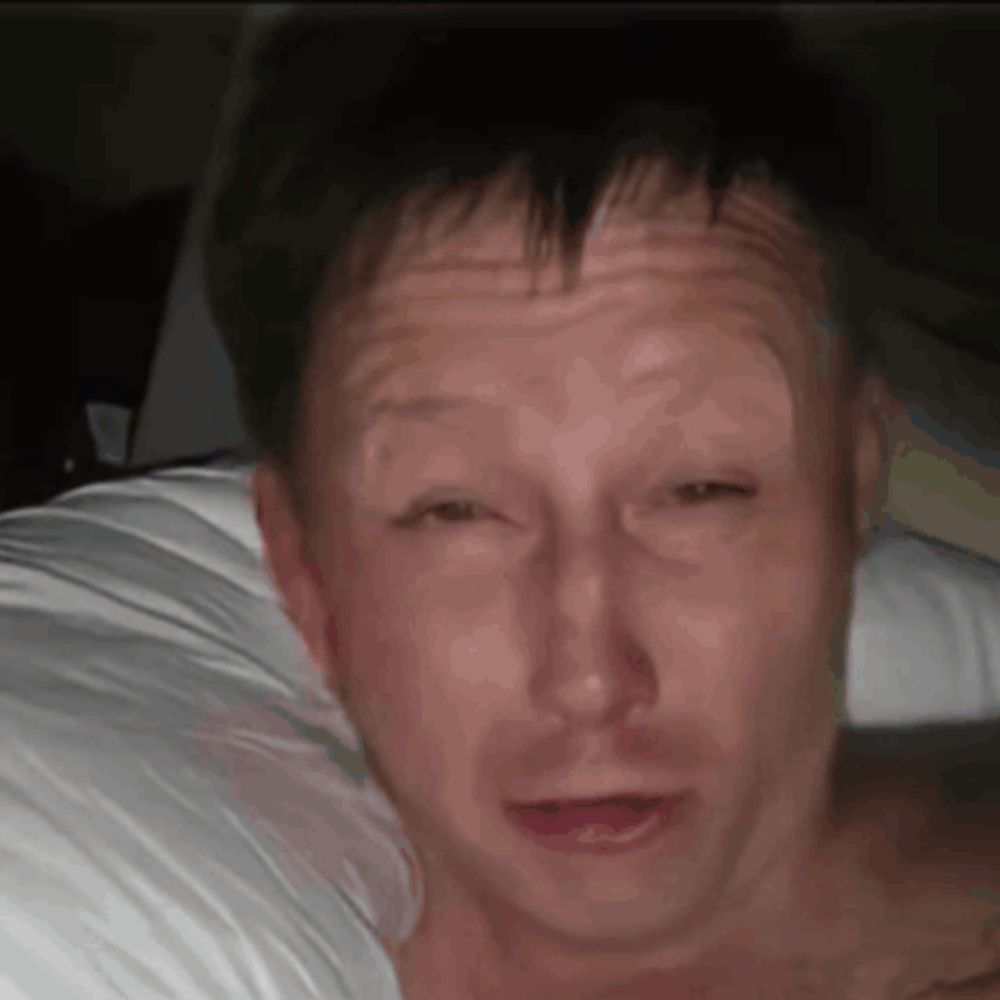 a man is laying on a bed with his eyes closed and his mouth open