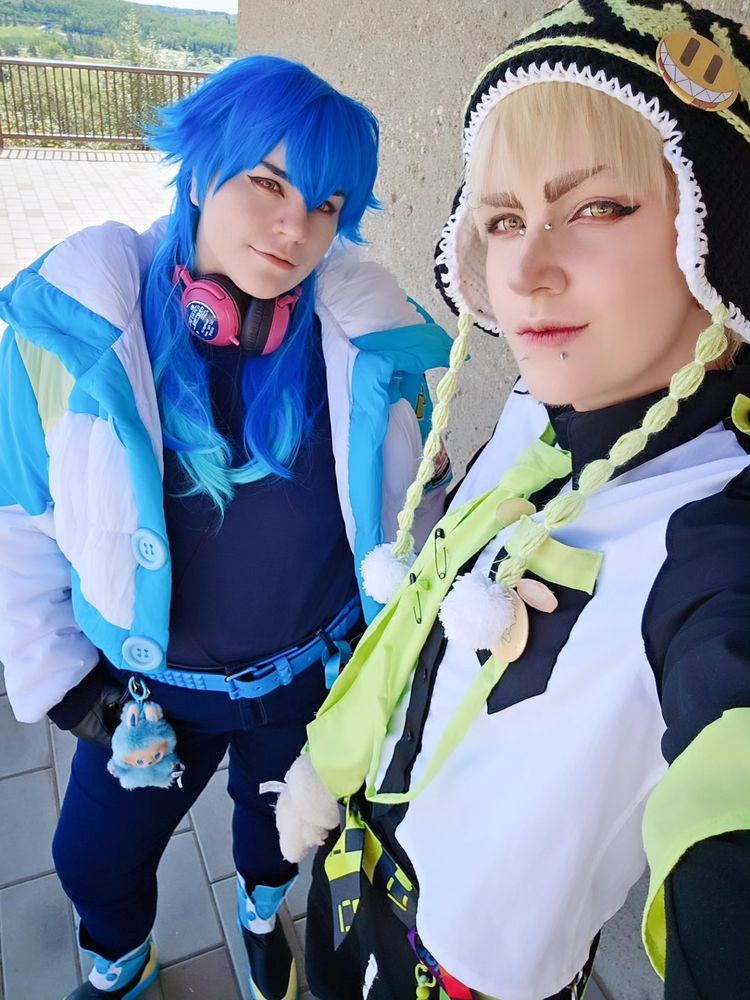 A selfie of an aoba seragaki cosplayer and a noiz cosplayer. They have labubus on their belt loops 