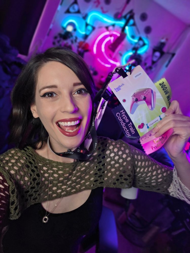 Char in her stream room holding up her twitch con badge. 