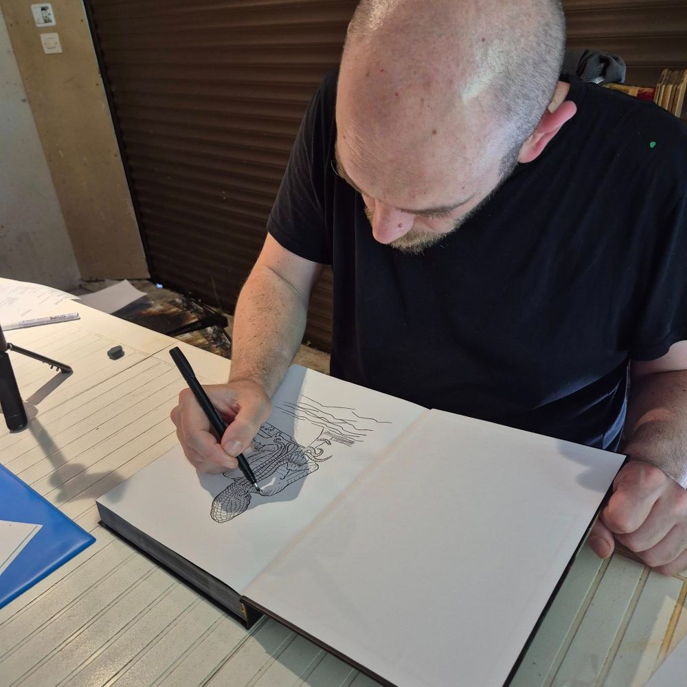 Benjamin réalise une illustration dans un manuel.