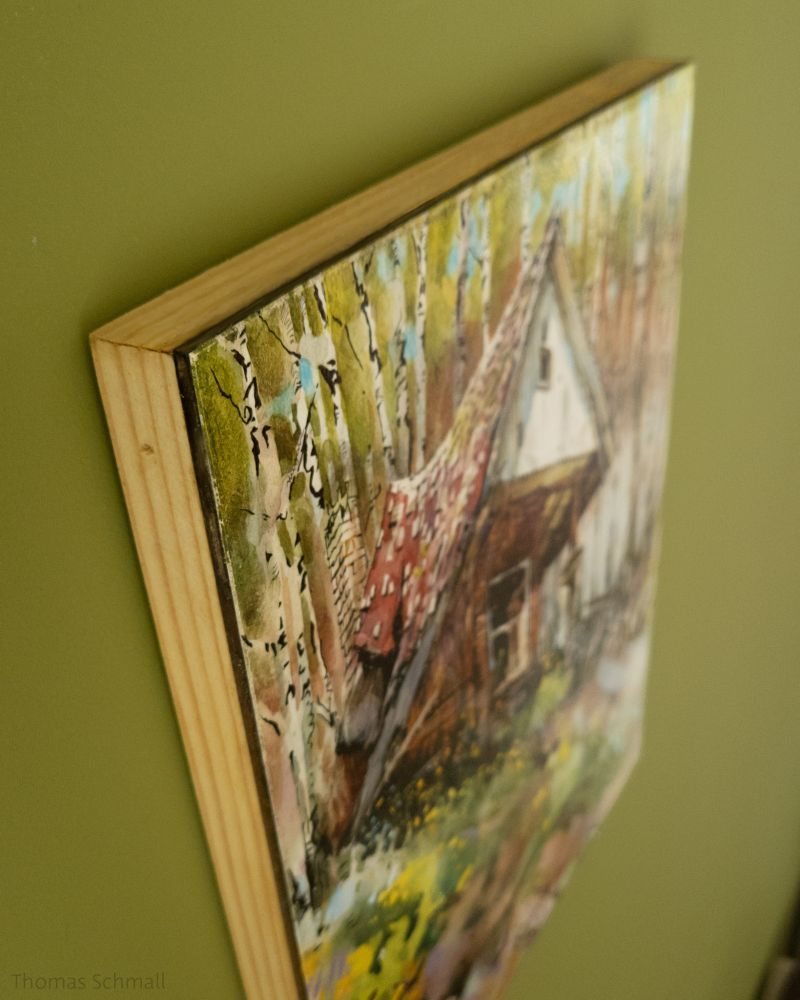 Forest hut painting hanging on a green wall. 