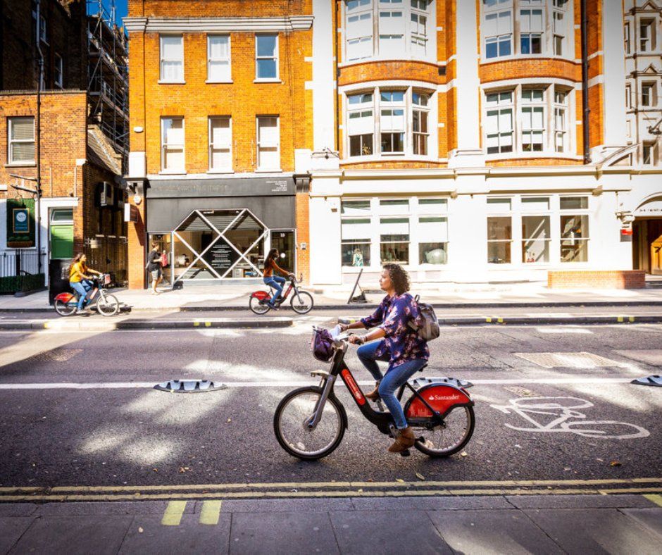 a person riding a Santander Cycles bike down a city street

