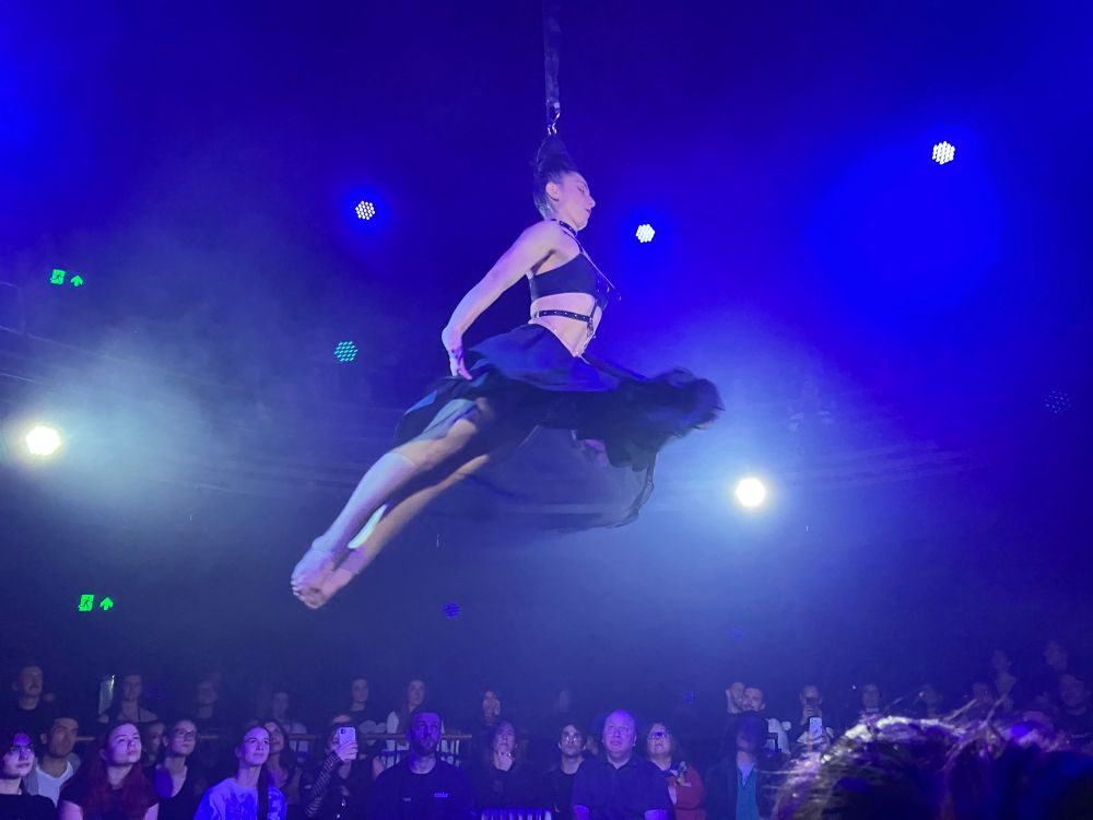A female aerialist suspended by her hair.