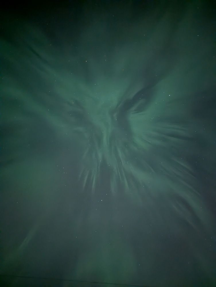 Streams of greenish northern lights flowing together in a triangle-ish pattern