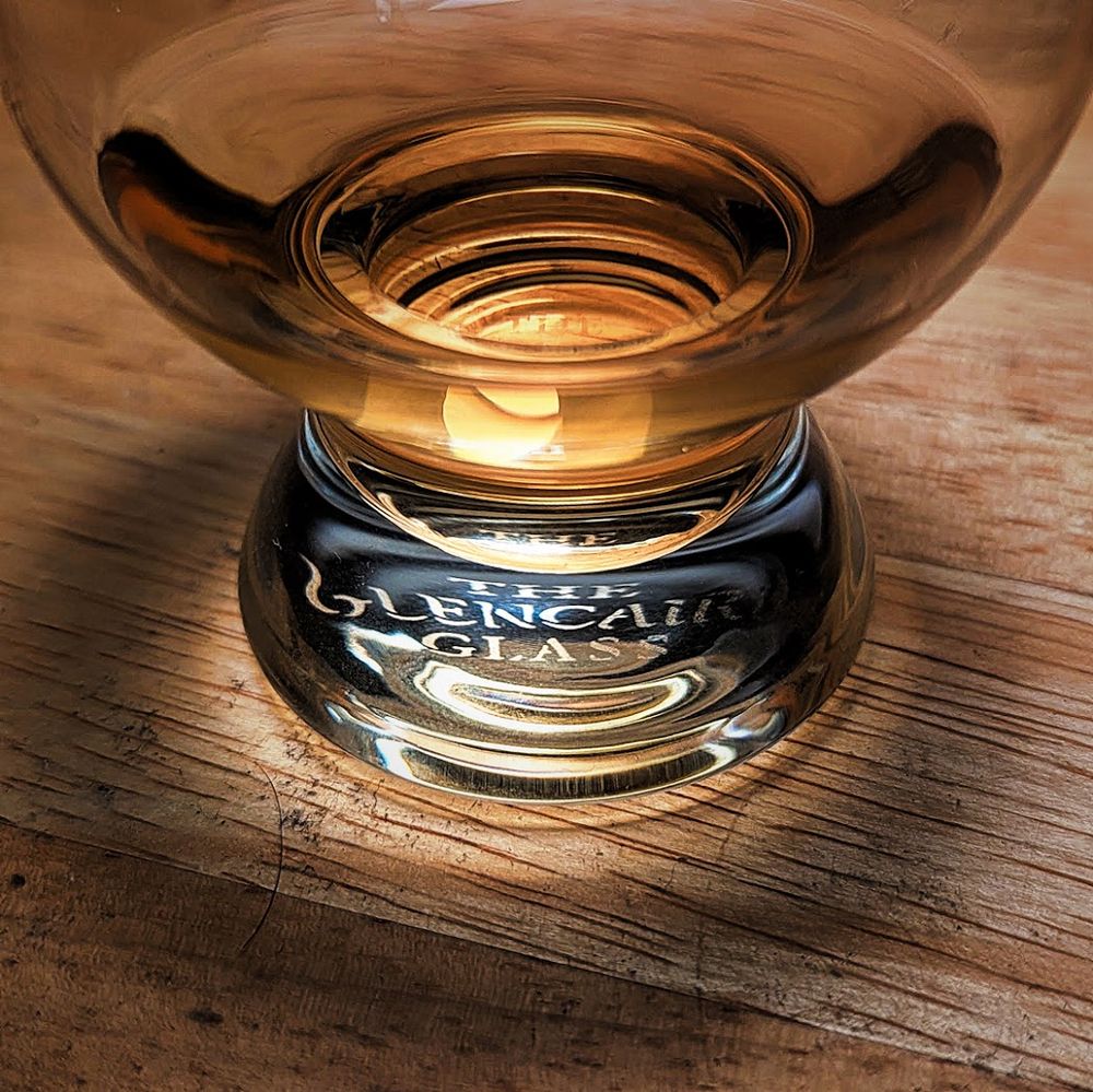A close-up of the base of a Glencairn glass containing a measure of whisky.