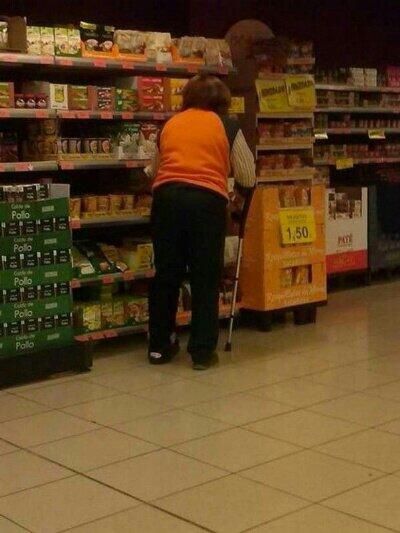 Trabajadora de Mercadona reponiendo estanterías con una muleta y una férula en el pie.