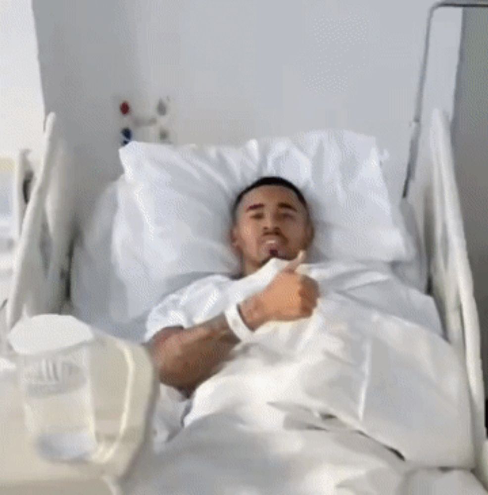 a man in a hospital gown is giving a thumbs up