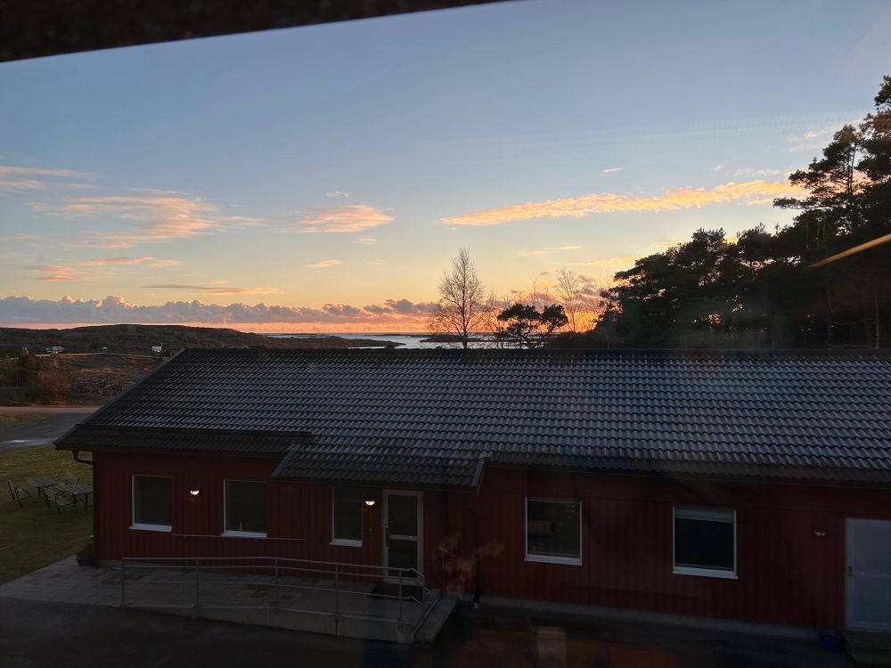 View out my office window at sunset. Can see the sea just over the top of a building in the foreground. The roof off the building still has frost on it at the end of the day!