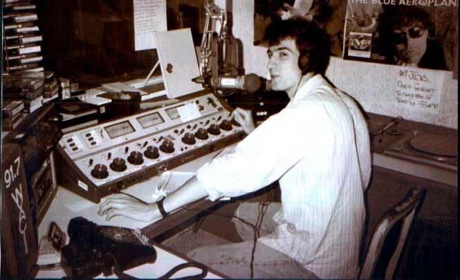 Vintage image of WXCI DJ Michael Wright sitting behind a mixing board and microphone. 