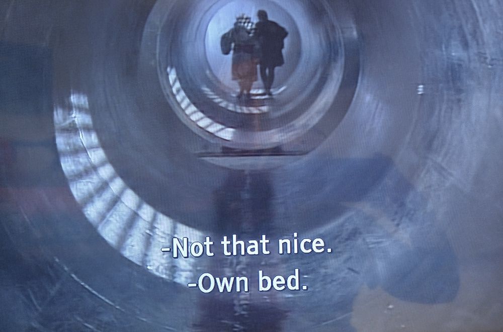 A screenshot from The Happiness Patrol which includes the subtitle 'own bed'.
