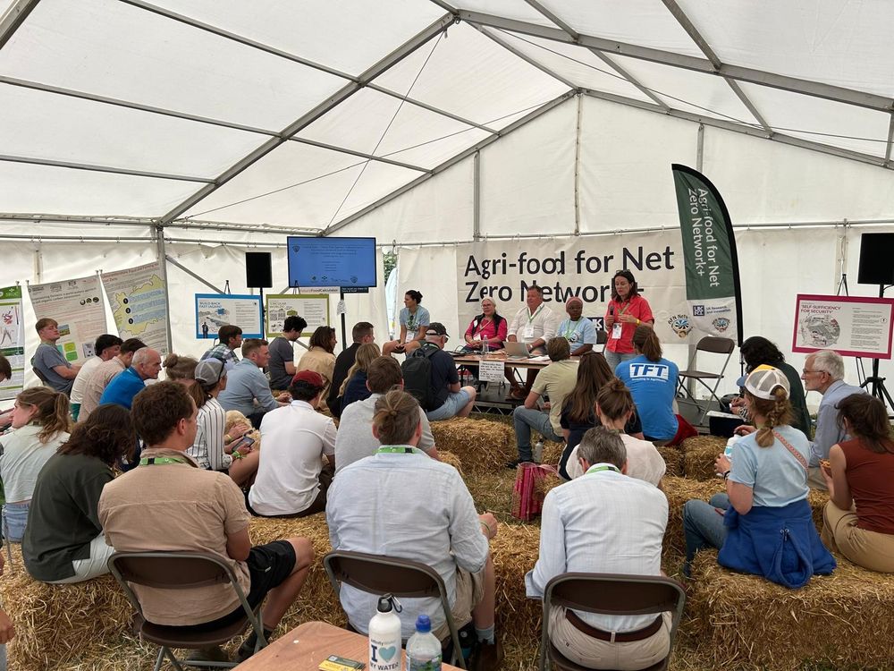 audience still on haybales and listen to a discussion at the afn network tent