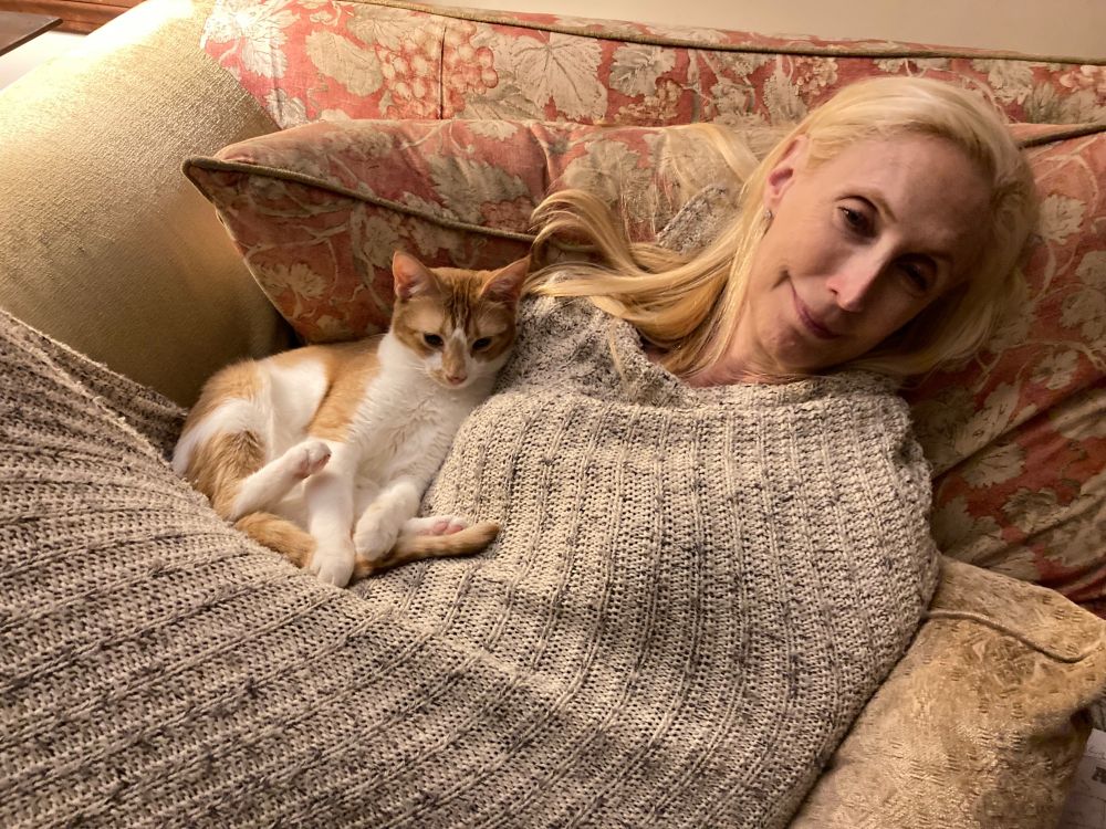 An orange tabby cat named Sunday curls up and gets cozy with her favorite mom. 