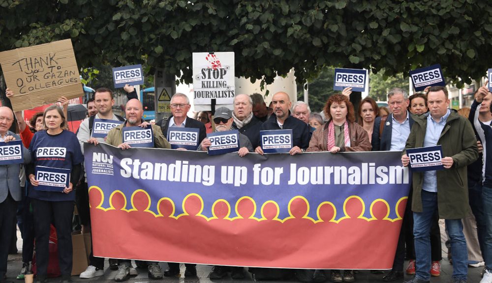 NUJ members at vigil for journalists killed in Gaza, holding large banner that reads, 'Standing up for journalism', as well as cards that read, 'Press freedom for Gaza now.'