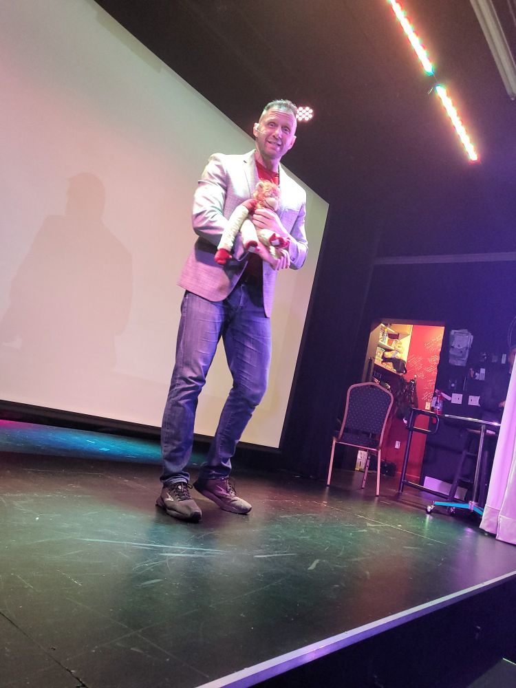 Nigel McGuinness on stage holding Bryan Danielson (in stuffed monkey form)