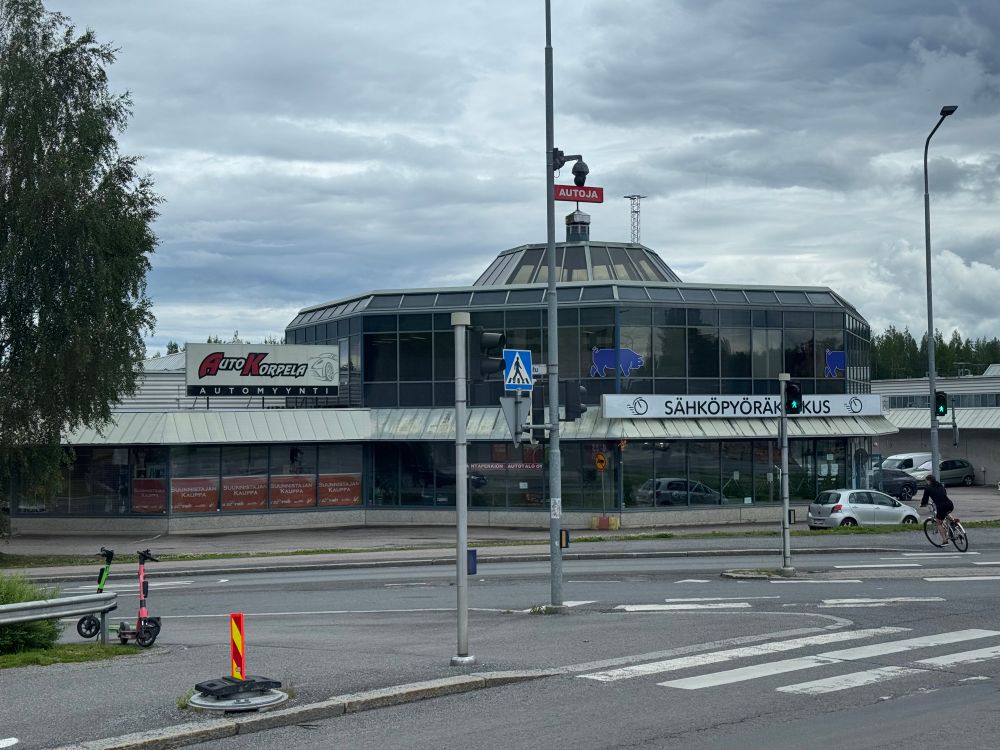 Old car store with car sales signs, but some of them already exchanged with electric bike store signs and ads.