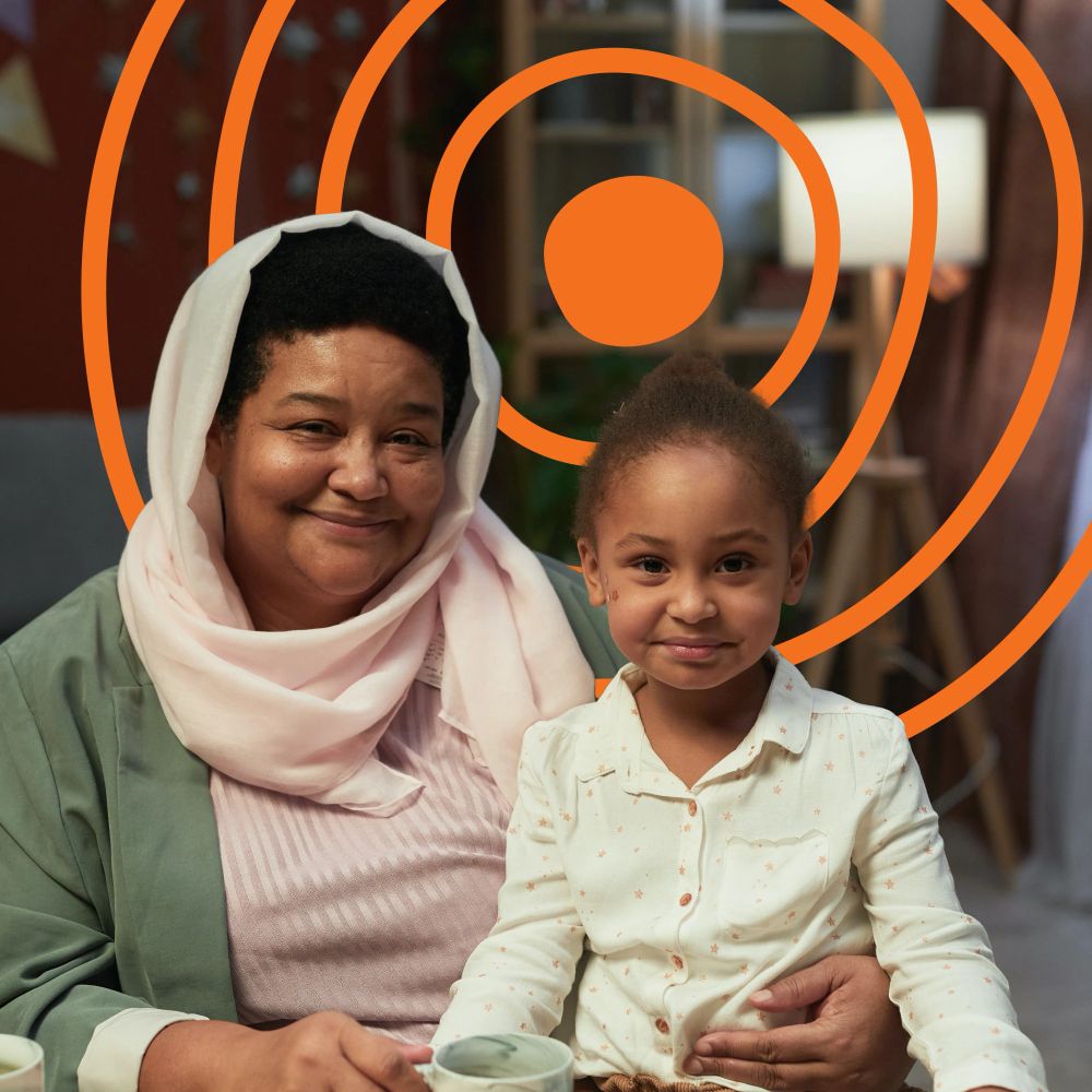 An older mother with her younger daughter on her lap, both smiling at the camera. The UN Decade of Healthy Ageing logo is in the background.