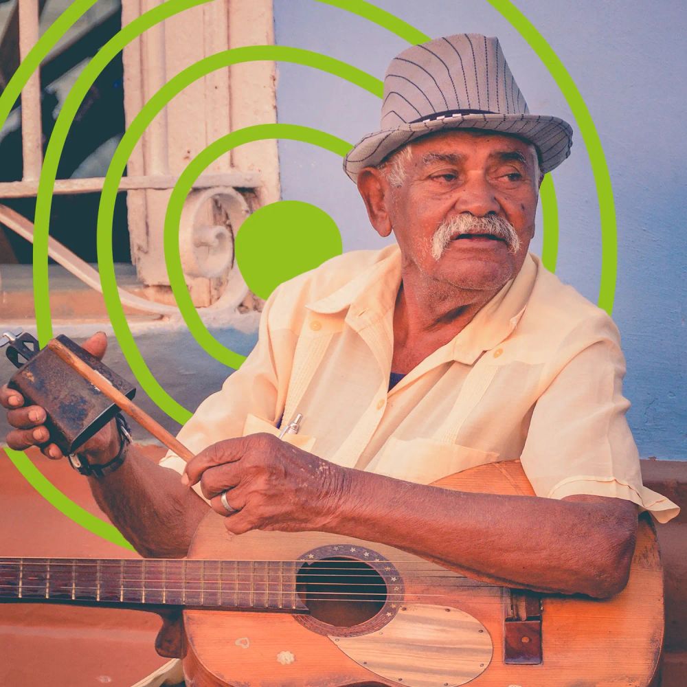 An older man playing a guitar and cowbell outdoors. The UN Decade of Healthy Ageing logo is in the background.
