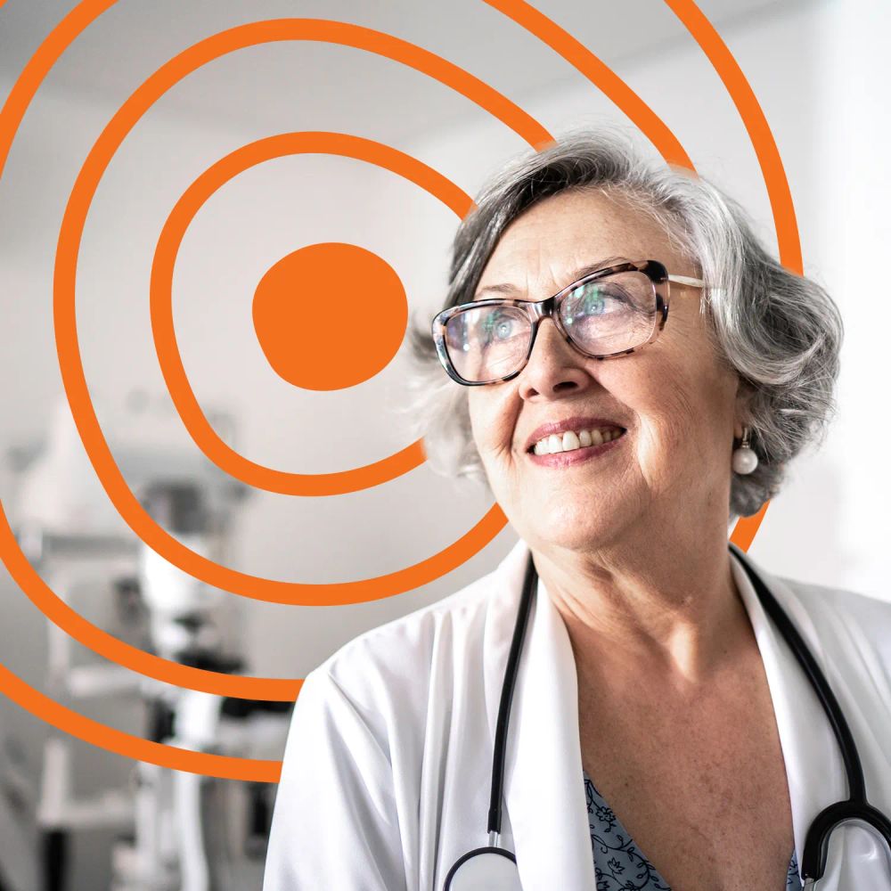 An older woman, who is also a doctor, smiling while looking out a window in her clinic. The UN Decade of Healthy Ageing logo is in the background.