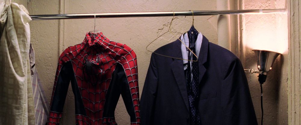 Frame from Spider-Man 2 of Peter's closet with his Spider-Man suit on one hanger to the left and his dress suit and tie on a hanger to the right.