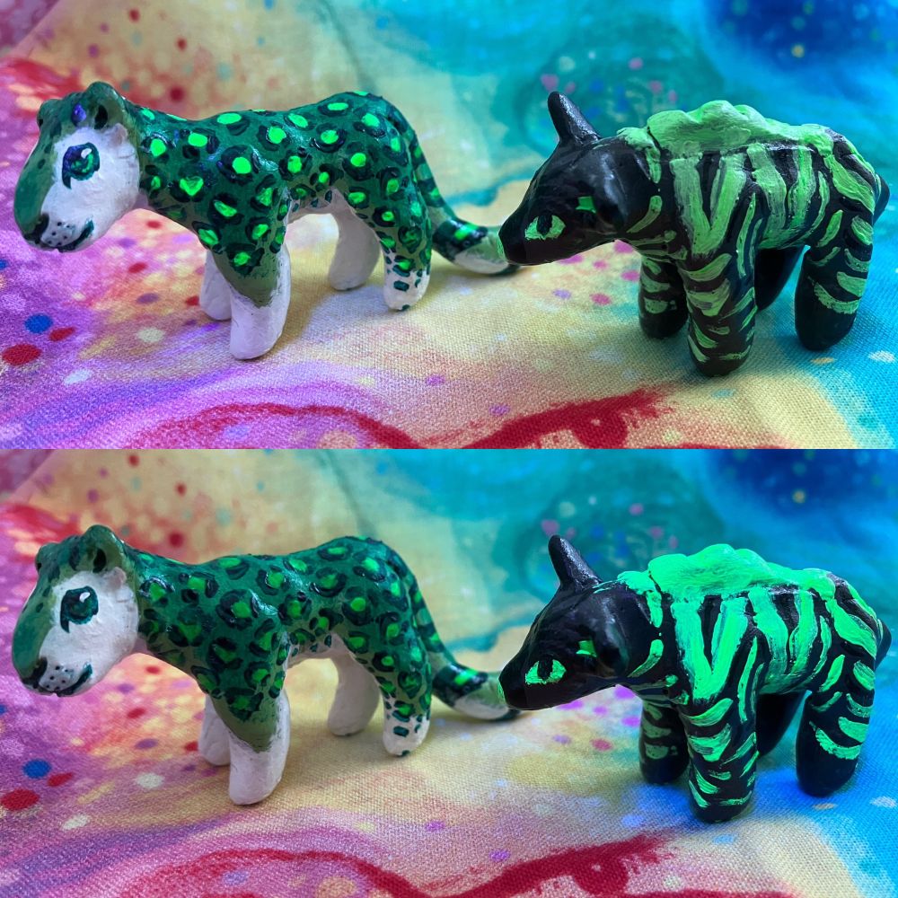 A photo of two sculptures, both mainly green, one is a striped hyena (yeen)and the other is a snow leopard (snep). Two views of them as shown, once under black light and the other under natural light