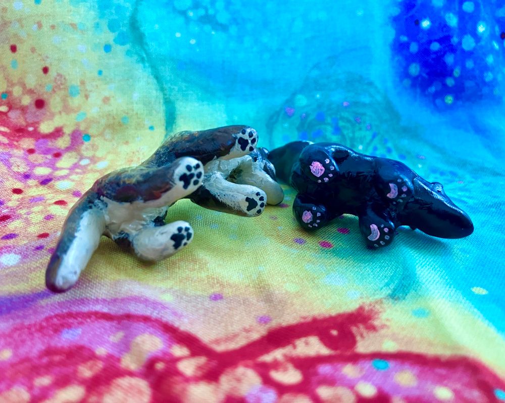 A pair of handmade sculptures (made with polymer clay and painted with acrylic paint) of a spotless genet and a striped skunk. 