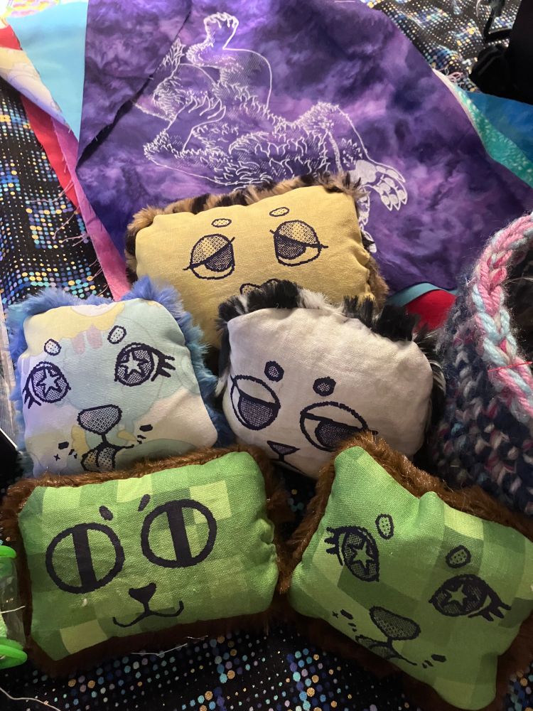 A pile of hand sew plushes with handprinted faces
