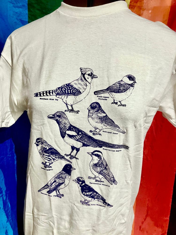 A collection of handprinted (hand screen printed) shirts in purple ink featuring a collection of Albertan bird species