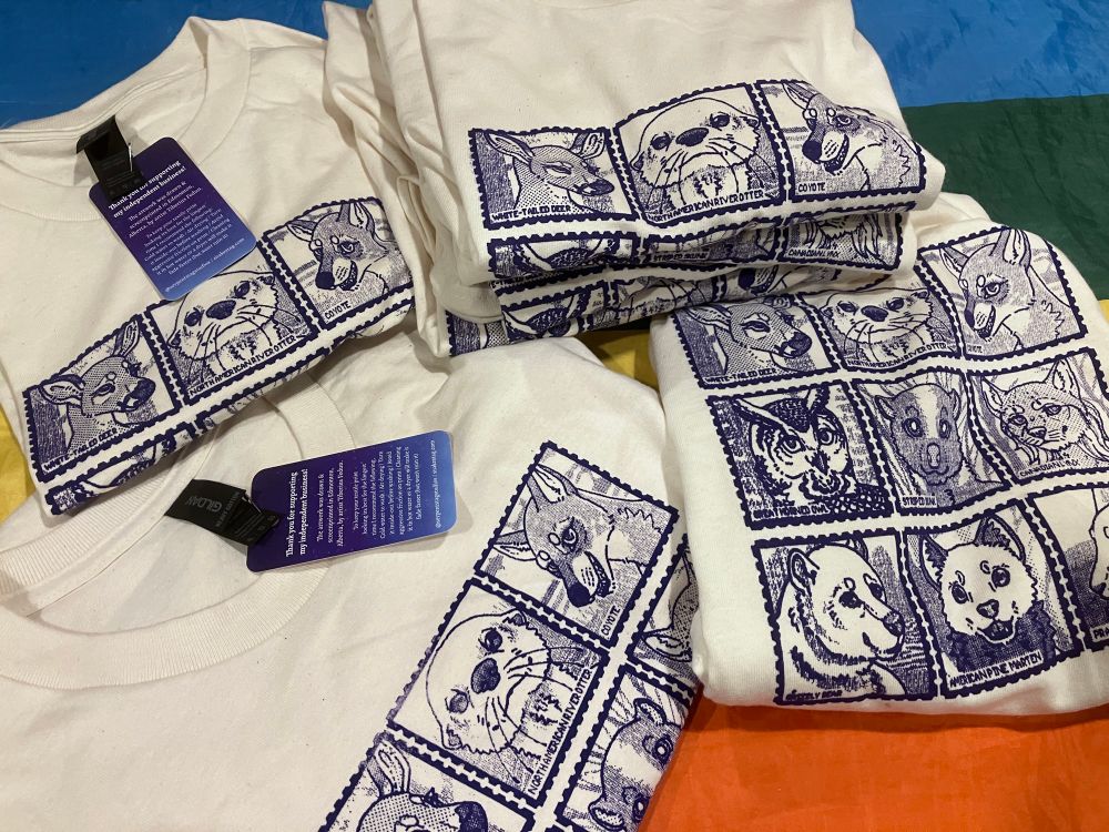 A collection of handprinted (hand screen printed) shirts in purple ink featuring a collection of Canadian animals on stamps