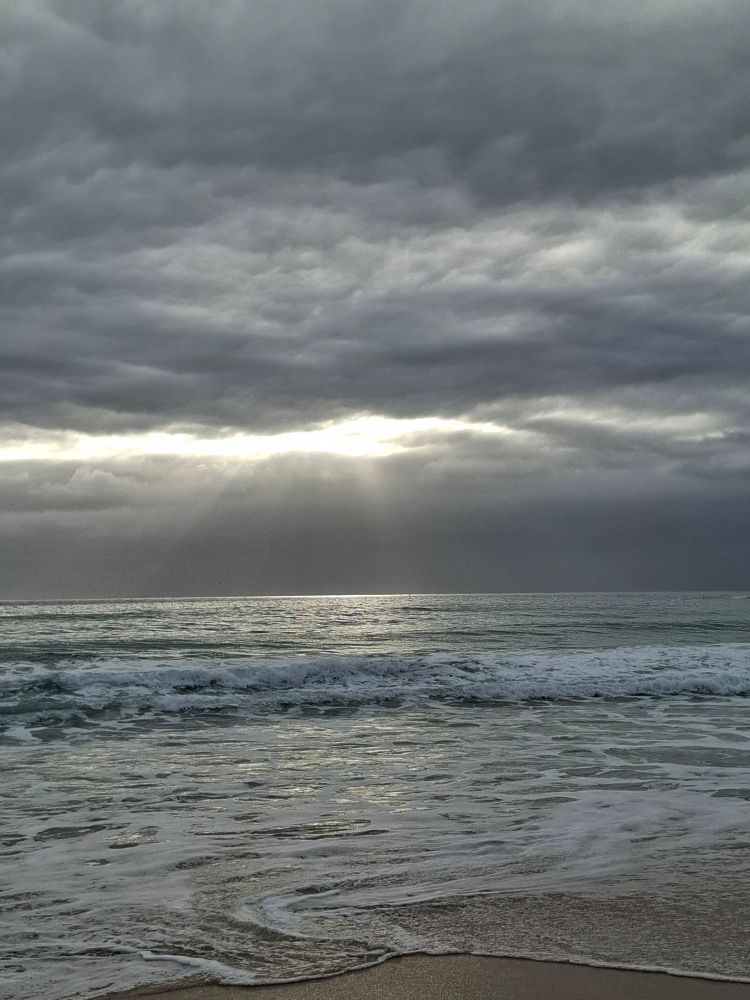Sunshine sneaking rays of light onto a shimmering sea.