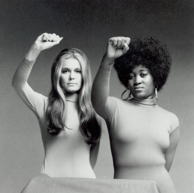 Gloria Steinem and Dorothy Pitman Hughes, with their fists in the air. One of these women has clearly used a fist before, the other has clearly not.