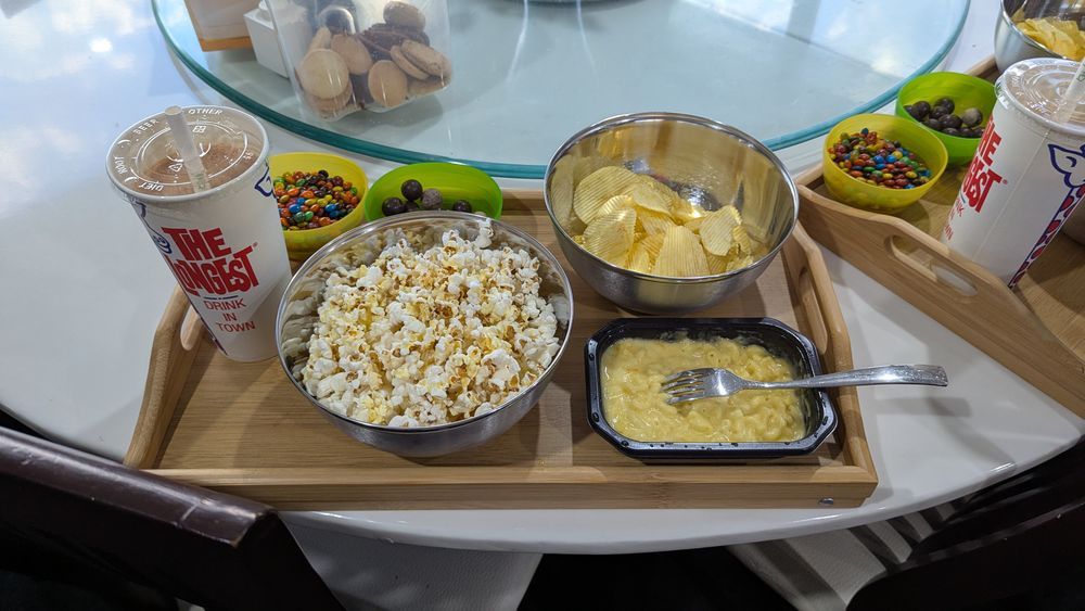 A milkshake, popcorn, M&Ms, Malteses and chips on a tray