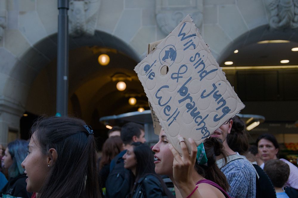 Demonstration, eine Frau hält ein Schild hoch mit der Aufschrift: Wir sind jung und brauchen die Welt