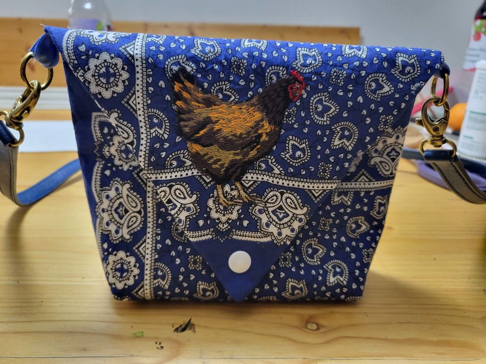 Kleine Handtasche aus einem Blau-Weiss-Gemusterten Halstüchlein. Vorderseite mit einem aufgestickten Huhn